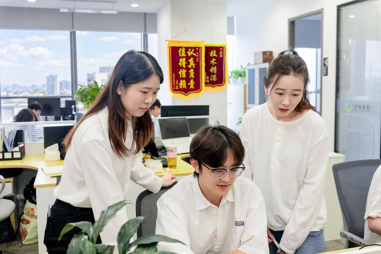 同事围坐在电脑前交流工作